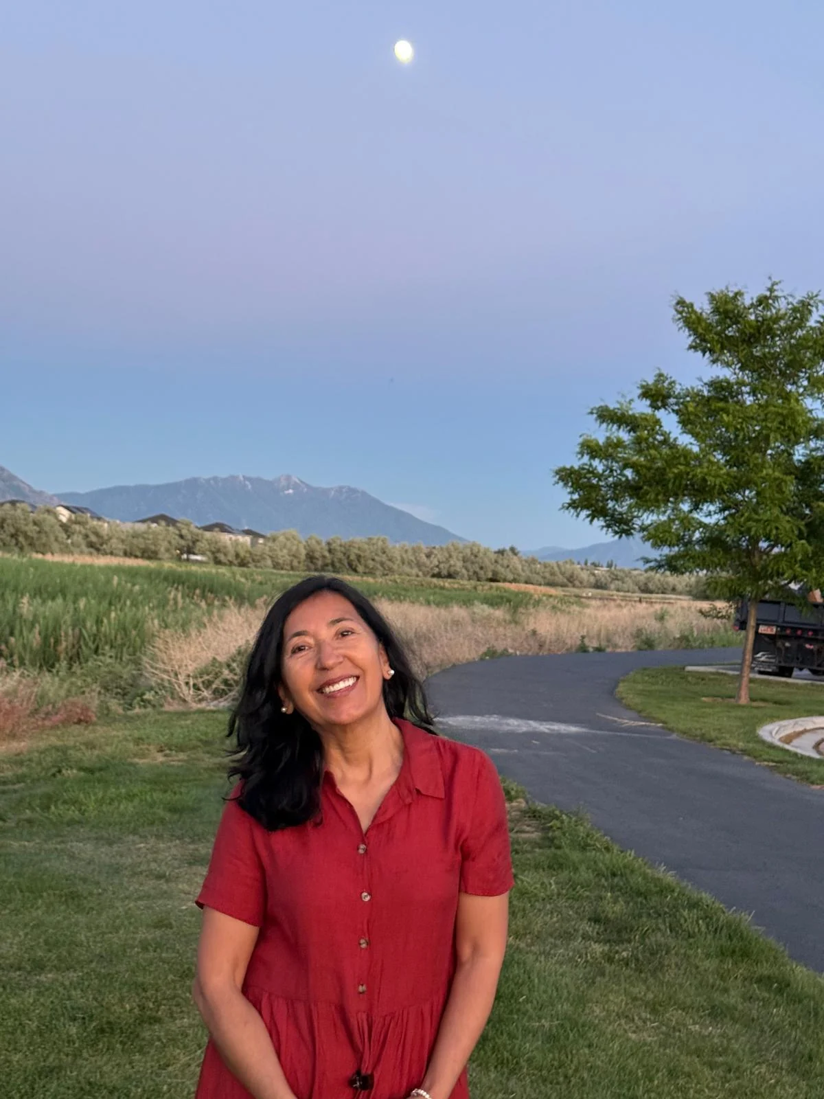 Nancy sonriendo al aire libre, con montañas al fondo